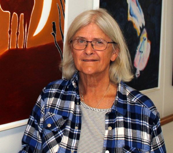 Inge Schønherr kunstner dame med briller og lyst hår foran nogle af sine værker