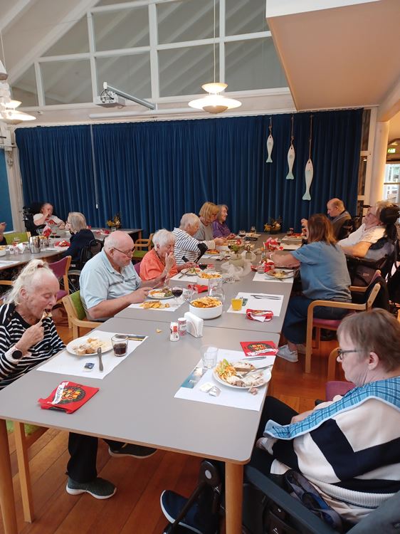 Beboere, pårørende og personale sidder i cafeen på Tolleruphøj og spiser heltstegt pattegris