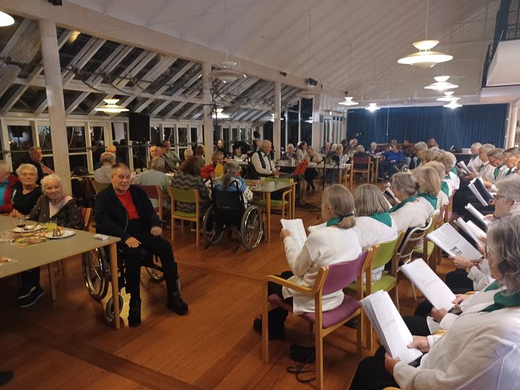 Beboere og pårørende lytter til Lundebjerggård koret i cafeen