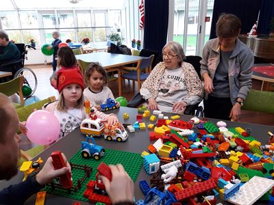 børnehavebørn og beboere og frivillige leger med Lego